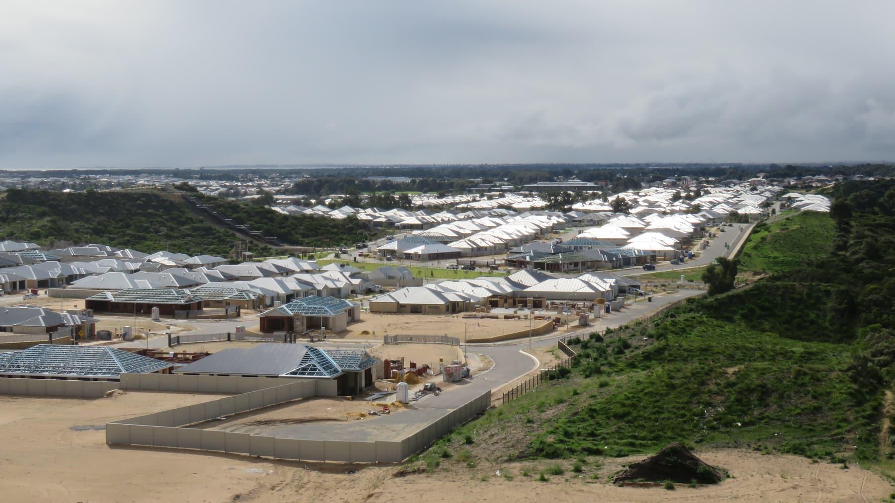 A new housing estate under construction, with roads, house frames and completed roofs.